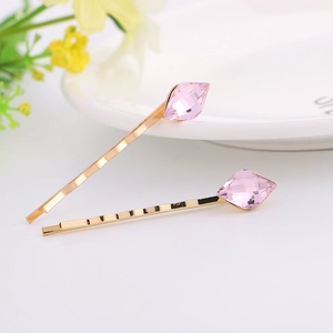 Set of two gold-plated hair clips with faceted pink crystals on a white surface