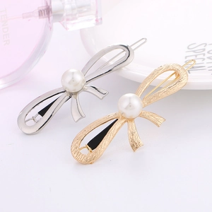 Detailed close-up of gold and silver bow hair clips with pearls on a decorative tray