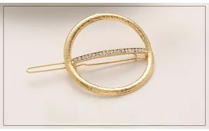 Close-up of golden hollow circle hair clip with sparkling rhinestones and hammered texture