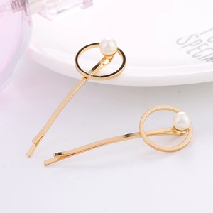 Détail de deux barrettes géométriques dorées avec perles blanches sur fond minimaliste