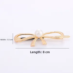 Detail view of golden bow hair clip with white pearl, dimensions 8cm length and 1.5cm width