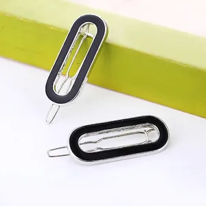 Detail of two black enamel oval hair clips on silver metal base for women's styling
