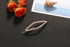 Detailed shot of a gold-plated leaf-shaped hair clip encrusted with sparkling rhinestones