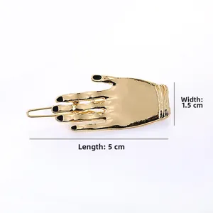 Dettaglio della clip per capelli a forma di mano dorata con dimensioni 5 cm x 1,5 cm