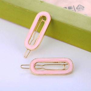 Detail of pink enamel oval hair clips with gold metal frames and bobby pin structure