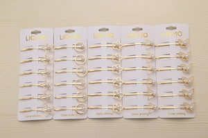 Détail de cinq barrettes dorées à perles en forme d'étoile, de cercle et géométriques
