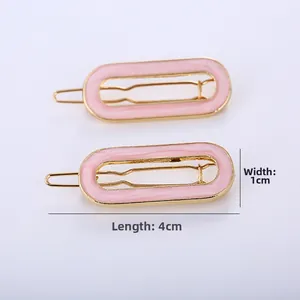 Detail view of pink enamel hair clips with gold metal frames measuring 4cm in length