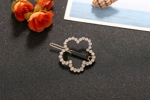 Detail of a gold-plated flower hair clip with sparkling white rhinestones and a back clip