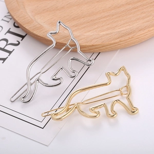 Minimalistische Haarspangen in Katzenform aus Gold und Silber auf Holztablett