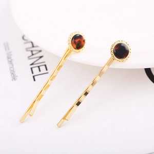 Detail of gold wavy hair clips with circular tortoiseshell accents on a white plate