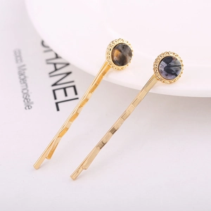 Detailed macro view of two gold wavy hairpins with marbled tortoiseshell pattern discs