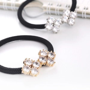 Close-up of sparkling zircon clover hair tie with black elastic band and silver base