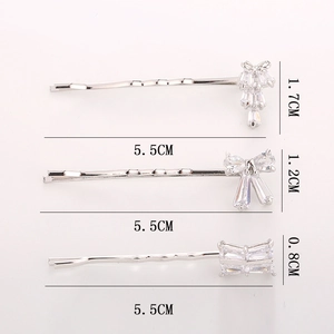 Three-piece silver bow hair clip set with sparkling cubic zirconia on a pink background