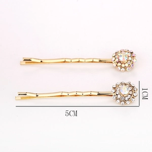 Lot de deux barrettes dorées avec design tournesol en strass sur un fond rose pastel