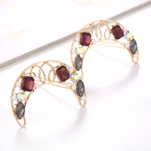 Macro detail of crescent moon hair clips with red crystals, pearls and gold finish