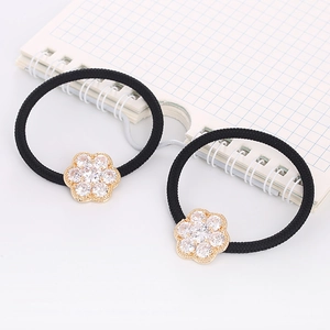 Close-up of two black high-elastic hair ties with sparkling zircon flower charms on white paper