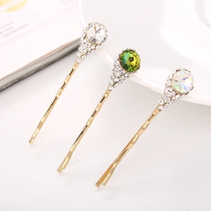 Détail de trois pinces à cheveux dorées avec cristaux colorés et strass brillants scintillants