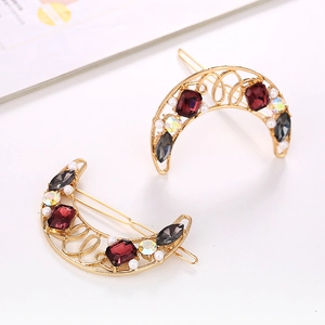 Golden moon-shaped hair clips set with crystals and faux pearls on white background