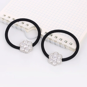 Close-up of black elastic hair ties with sparkling zircon flower charms on a notebook