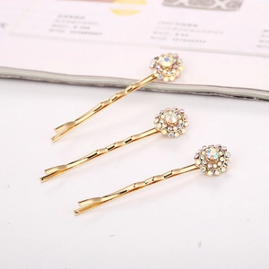 Détail de barrettes dorées ondulées avec fleurs en cristal et strass de couleur aurore