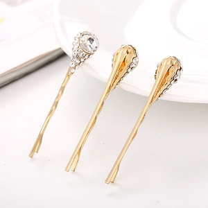Détail de trois barrettes à fleurs dorées ornées de cristaux et de strass scintillants