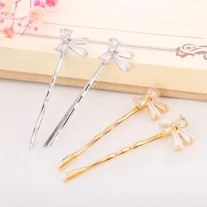 Close-up of gold and silver bow hair clips with zircons on a notebook background