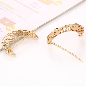 Detail view of gold crescent moon hair clip with hollow floral pattern and single needle pin