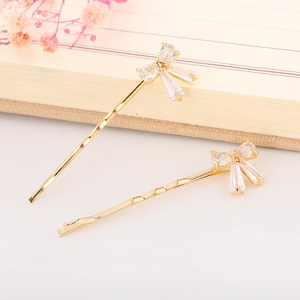 Detail of elegant gold wave hairpins with crystal bow tie and zircon stone accents
