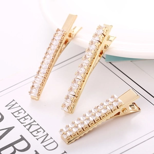 Close-up of three gold duckbill hair clips set with shiny rectangular zircons in a set