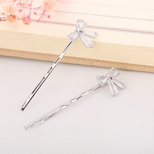 Detailed view of handmade bow hairpins with sparkling zircons on a wavy metal base