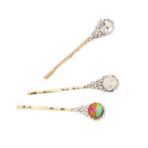Trois barrettes dorées ornées de cristaux scintillants et de diamants sur fond blanc