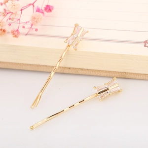 Close-up of golden bar hair clips with rectangular zircon crystals on a notebook