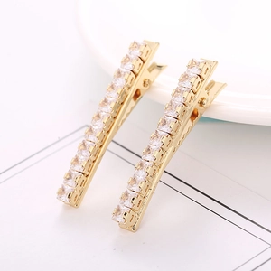 Close-up of golden hair clips featuring a row of square-cut sparkling zircons