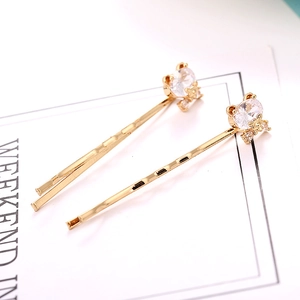 Detailed macro view of two golden hair clips featuring bear-shaped clear zircon crystals