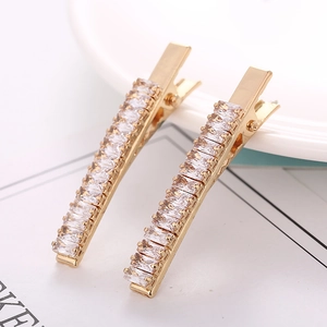 Detailed close-up of a pair of gold-plated alligator hair clips with baguette zircon stones