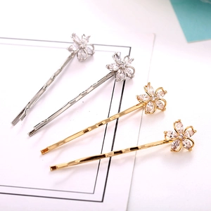 Detail showing four zircon flower hair clips in gold and silver finish on white card