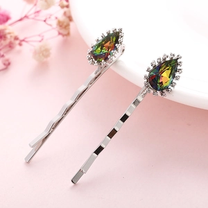 Close-up of teardrop rainbow crystal hair clips with sparkling rhinestones on pink background