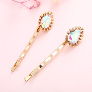 Elegant gold wavy hair clips with colorful teardrop crystals on a pink background