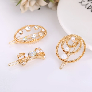 Détail de barrettes dorées avec perles blanches et strass colorés sur une assiette blanche
