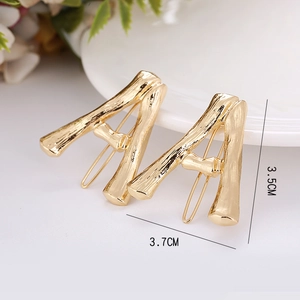 Detailed close-up of golden letter A hair clips with bamboo texture and 3.7cm size details