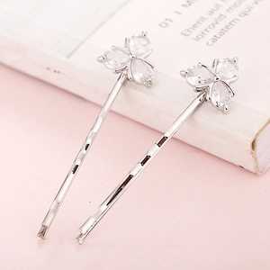 Détail de barrettes argentées avec zircons en forme de poire formant un motif de trèfle