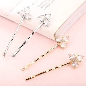 Gros plan de barrettes à fleurs dorées et argentées avec cristaux sur fond rose