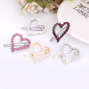 Dettaglio di fermagli per capelli a forma di cuore con strass rosa e perle bianche