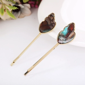Detail view of gold-plated hair pins with marbled resin and shell-shaped stone texture