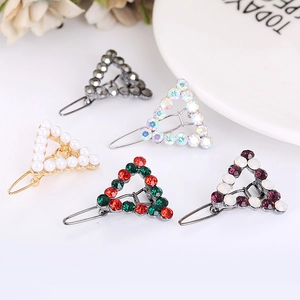 Set di cinque eleganti fermagli a triangolo con strass colorati e perle su uno sfondo bianco