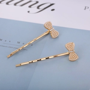 Detail shot of golden bow hair clips with white pearls and sparkling crystals on blue card