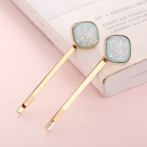 Set of two gold alloy hairpins with square light blue glitter sequins on pink background