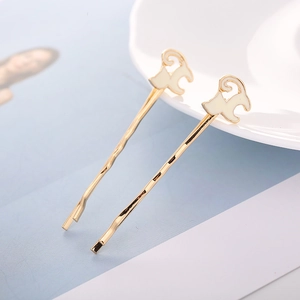 Elegante goldfarbene Haarklammern mit weißen Emaille-Tierformen im minimalistischen Stil