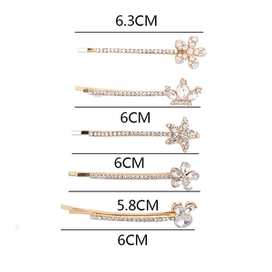 Elegantes Haarspangen-Set in Gold mit Strass, Stern, Krone und Schleife auf weißem Grund