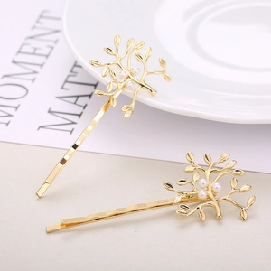 Detailed view of two golden tree-shaped hair pins featuring elegant white pearls
